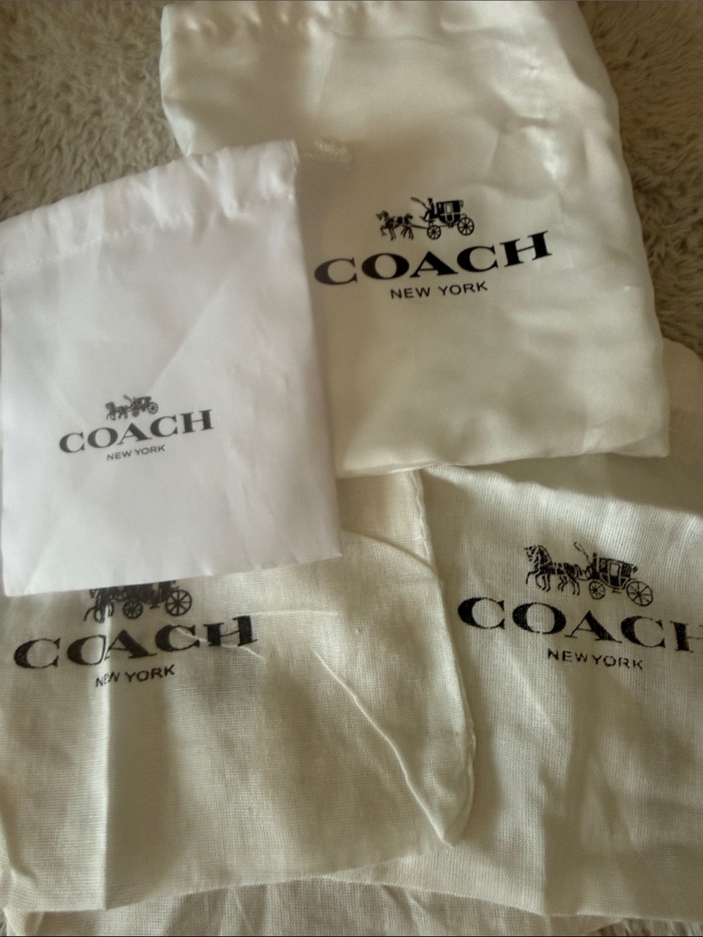 bottle of five Coach dust bags